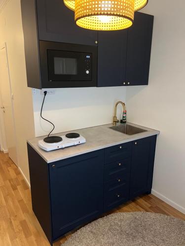 eine Küche mit einer Theke mit Spüle und Mikrowelle in der Unterkunft Small studio apartment in the city center in Trollhättan