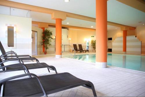 un hall d'hôtel avec une piscine et des colonnes orange dans l'établissement Weltenbummler Lodge in Schwarzenberg, à Schwarzenberg/Erzgebirge