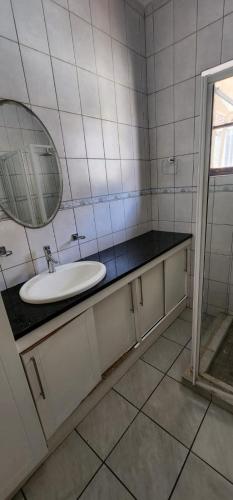 a white bathroom with a sink and a mirror at 18 Laburnum Lodge in Durban