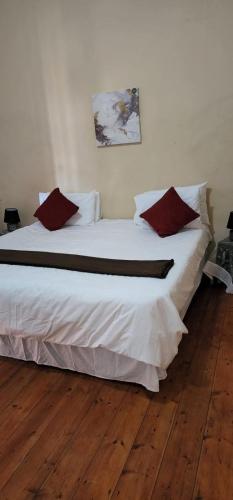 a bedroom with a large white bed with red pillows at 18 Laburnum Lodge in Durban