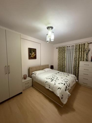 une chambre avec un lit et un lustre dans l'établissement Nene Tereza Airport Apartment, à Valjiosi