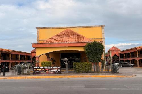 a yellow building with a tile roof on a street at Hotel Mirage Express in Matamoros