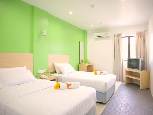 a hotel room with two beds and a television at T Hotel Kuala Perlis in Kuala Perlis