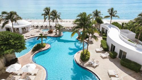 an aerial view of a resort pool with palm trees and the ocean at Trump International Beach Resort - Sunny Isles Beach in Miami Beach