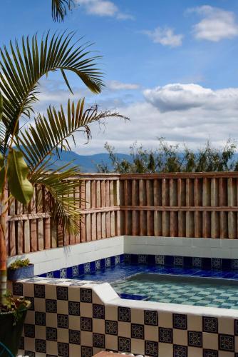 a swimming pool with a fence and a palm tree at El Diablo y La Luna B&B by El Diablo y La Sandia in Oaxaca City