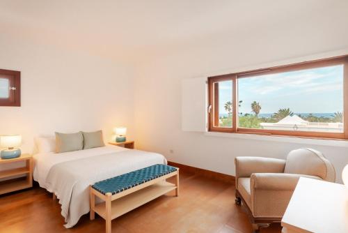 a bedroom with a bed and a window and a chair at Canaryislandshost l Pausa in Costa Teguise