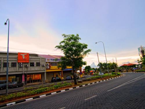 an empty street in a town with buildings and a tree at T Hotel Kuala Perlis in Kuala Perlis