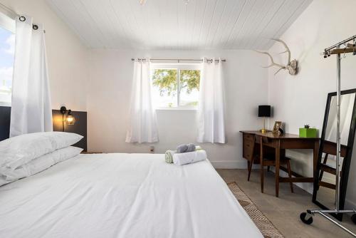 une chambre avec un grand lit blanc et un bureau dans l'établissement Rancho Relaxo - hot tub, fire pit, open air bath and comfy beds, à Twentynine Palms