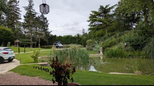 Vista de un jardín con un estanque y un coche en L'atelier, en Festigny