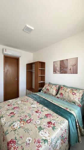 a bedroom with a bed with a floral bedspread at Seu Descanso a Beira Mar in Ilhéus