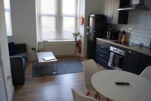 a small kitchen with a table and a kitchen with a refrigerator at Luxury Apartment - Central Dundee - Pet Friendly in Dundee