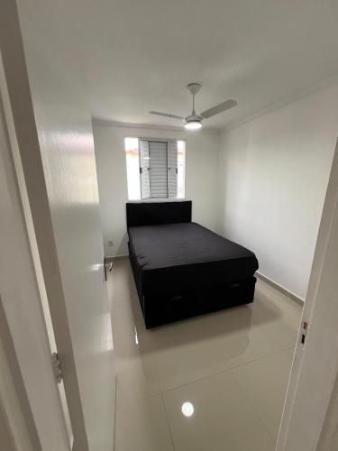 una camera da letto con un letto nero in una stanza bianca di Ape 2 quartos a Guarujá