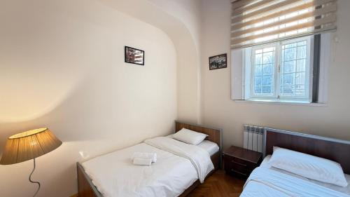 a bedroom with two beds and a lamp and a window at Old city apart in Baku
