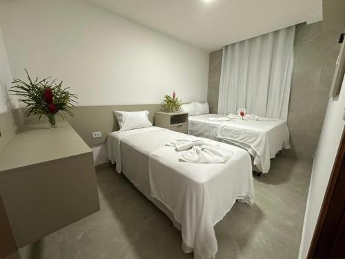 a hotel room with two beds with white sheets at Sanzé Flats - São José da C Grande in São José da Coroa Grande