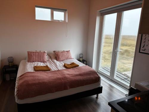 Un dormitorio con una cama y una ventana grande en Hamar - Puffin Cottages & Rooms, en Hvolsvöllur