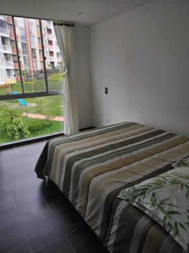 una cama en una habitación con una ventana grande en Tranquilan-dias, en Guaduas