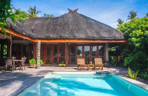 een villa met een zwembad en een rieten dak bij Balai sa Baibai in Mambajao