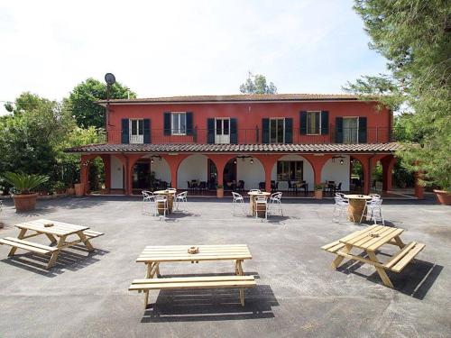 un grupo de mesas de picnic frente a un edificio rojo en Il bracconiere en Fonteblanda