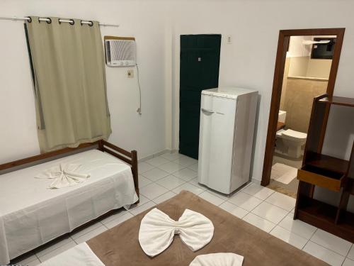 a small room with a bed and a refrigerator at Pousada Casarão - Pé na Areia Cumuruxatiba in Cumuruxatiba