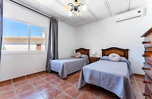 due letti in una stanza con una grande finestra di Villa Paula-Los Manantiales ad Alhaurín de la Torre
