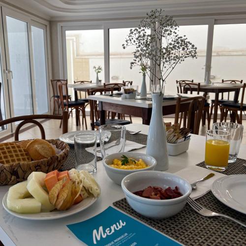 een tafel met ontbijtgerechten op een tafel in een restaurant bij Bombinhas Blue Suítes in Bombinhas