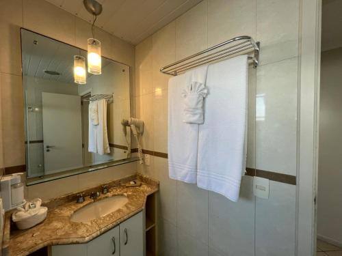 ein Badezimmer mit Waschbecken und Spiegel in der Unterkunft Bombinhas Blue Suítes in Bombinhas