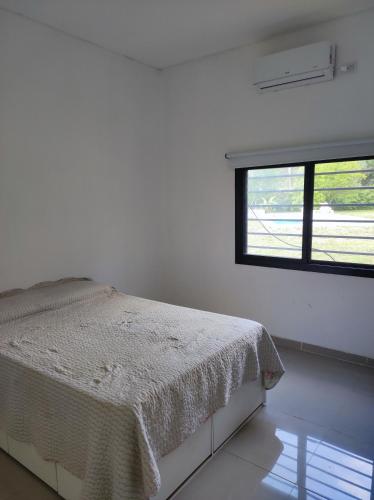 a white bedroom with a bed and a window at la morita silvestre in General Rodríguez