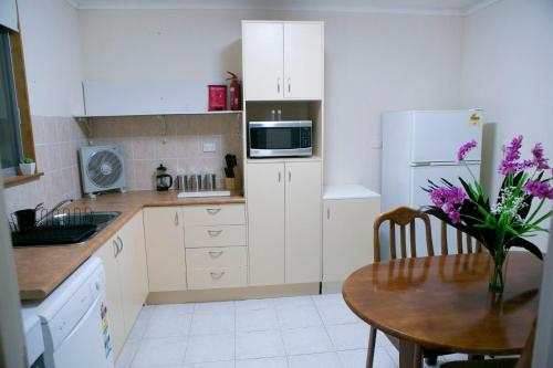 a kitchen with a table and a white refrigerator at Cave Place Units in Coober Pedy