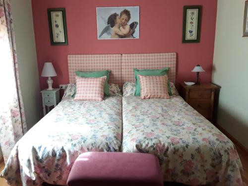 a bedroom with a large bed with pink walls at Las Glicinias del Jerte in Casas del Castañar
