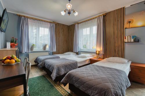 um quarto de hotel com duas camas e uma mesa em Zajazd Karłów Restauracja & Pokoje Gościnne em Karłów