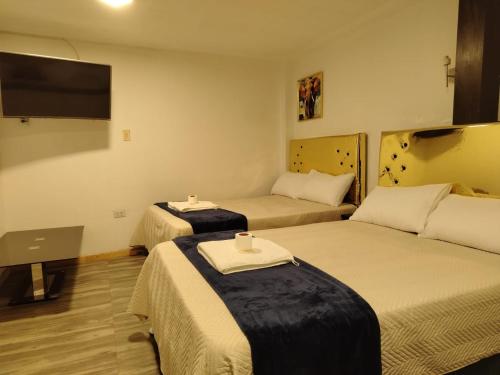 ein Zimmer mit zwei Betten und einem Flachbildfernseher in der Unterkunft Concubinas del Inca in Cajamarca