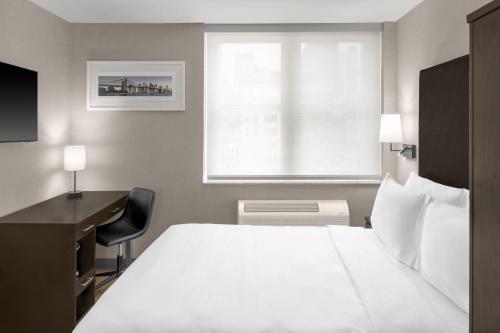 a bedroom with a bed and a desk and a window at Solita Soho Hotel in New York
