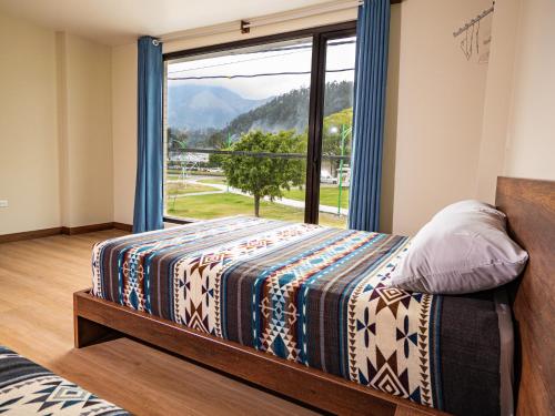 a bedroom with a bed and a large window at The Traveler Hostel in Otavalo