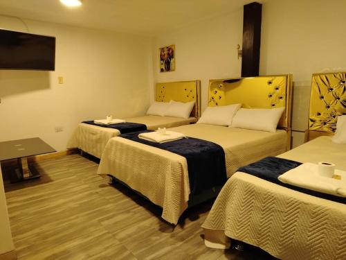 ein Hotelzimmer mit drei Betten und einem Flachbildfernseher in der Unterkunft Concubinas del Inca in Cajamarca