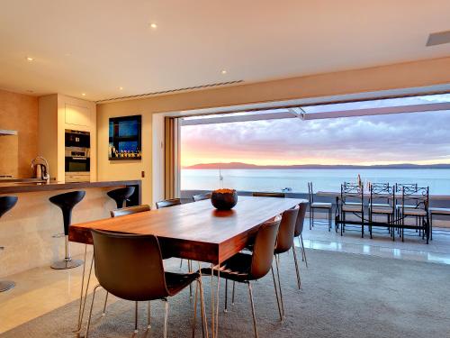 a dining room with a table and a view of the ocean at Amarna Luxury Beach Resort in Nelson Bay