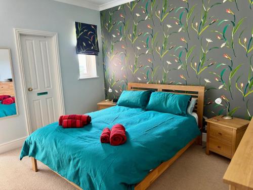 a bedroom with a blue bed with red roses on it at Spacious Edwardian home in Stroud