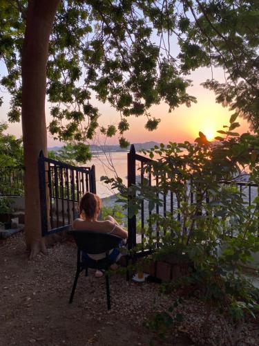una mujer sentada en una silla viendo la puesta de sol en Nile View House, en Asuán