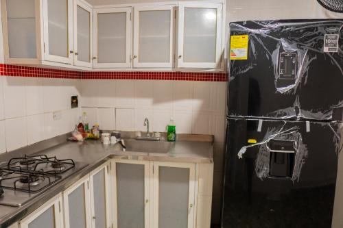 a kitchen with white cabinets and a black refrigerator at Casa Claro del Mar in Coveñas