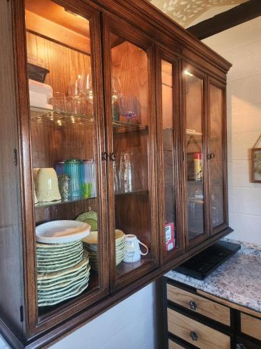 a wooden cabinet with plates and dishes in it at Quail Covey Cottage in Hereford Airport