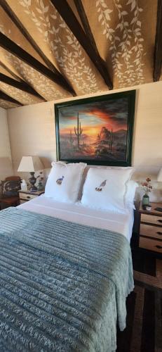 a bedroom with a bed with a painting on the wall at Quail Covey Cottage in Hereford Airport