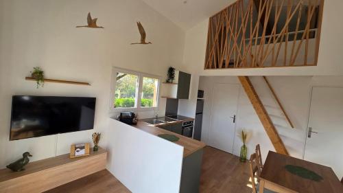 a living room with a tv and a kitchen at Cottage Atypique in Saint-Laurent-de-la-Prée