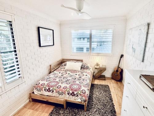 ein Schlafzimmer mit einem Bett und einer Gitarre darin in der Unterkunft Somerset Sunrise Townhouse in Byron Centre in Byron Bay