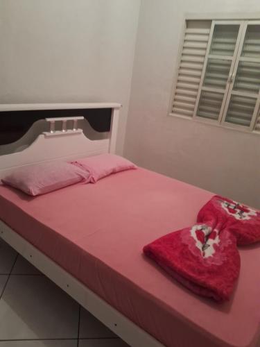 a bedroom with a pink bed with towels on it at Recanto feliz in São Thomé das Letras