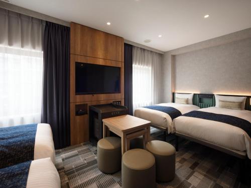 una camera d'albergo con due letti e una TV a schermo piatto di THE KNOT TOKYO Shinjuku a Tokyo