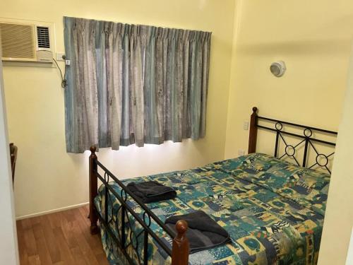 ein Schlafzimmer mit einem Bett mit blauer Bettdecke und einem Fenster in der Unterkunft Barrier Reef Tourist Park in Edmonton