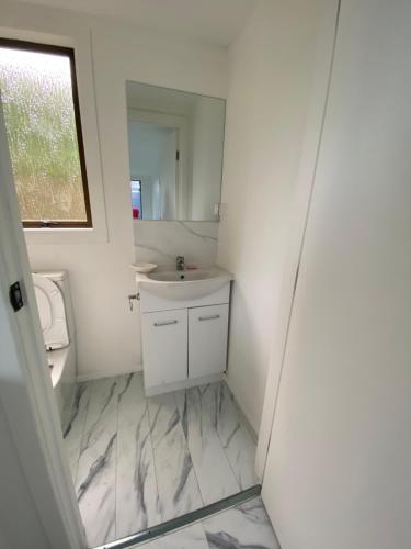 um banheiro branco com uma pia e um espelho em 2bed granny flat close to Auckland Airport em Auckland