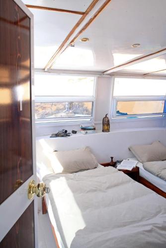 a bedroom with two beds and two windows on a boat at Nubiana Boat in Jazīrat Shāsh