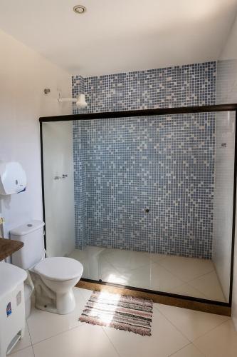 a bathroom with a glass shower with a toilet at Enseada Hostel in Arraial do Cabo