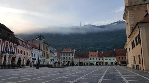 a city street with buildings and a mountain in the background at Studio Piata Sfatului - Brasov in Braşov