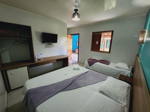a room with two beds and a flat screen tv at Pousada Bom Jardim in Estivado